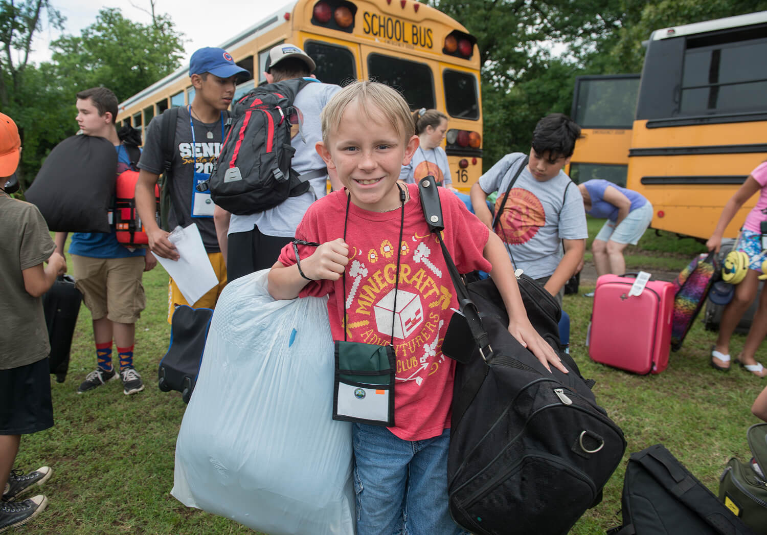 A cheerful young boy arriving eagerly to join a camp.