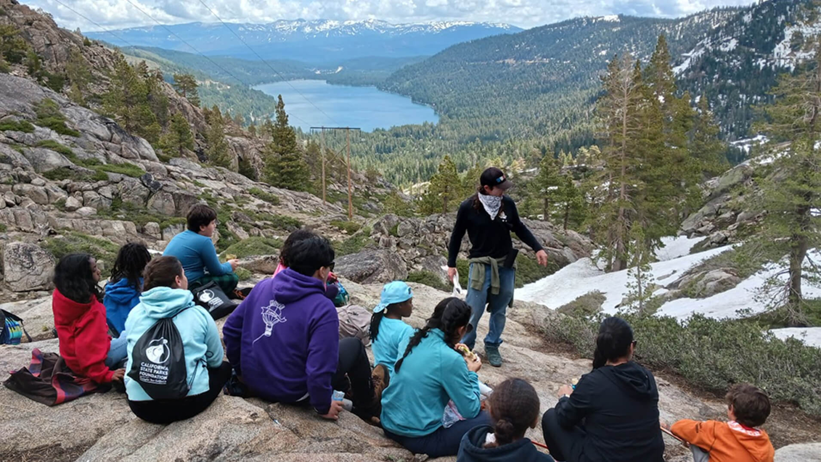 A group of young people camping in a scenic mountainous area.